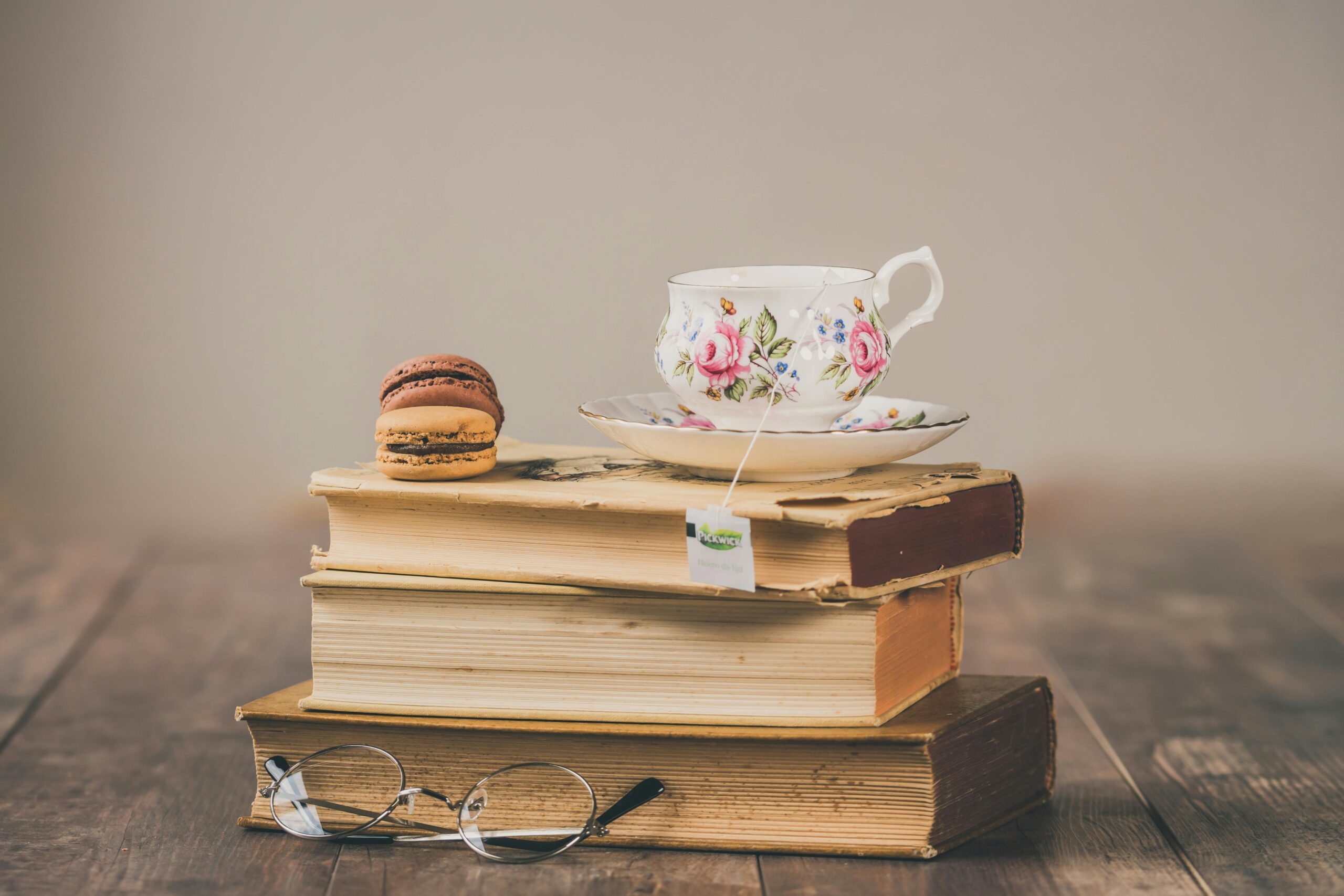 Elegant setup of floral teacup with macarons on a stack of vintage books.